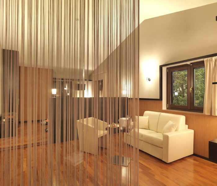 Suite di lusso all'Hotel Castagneto Melfi, dove design elegante e comfort si incontrano per un'esperienza unica. Interno elegante della Suite all'Hotel Castagneto Melfi con zona salotto moderna e finiture in legno.