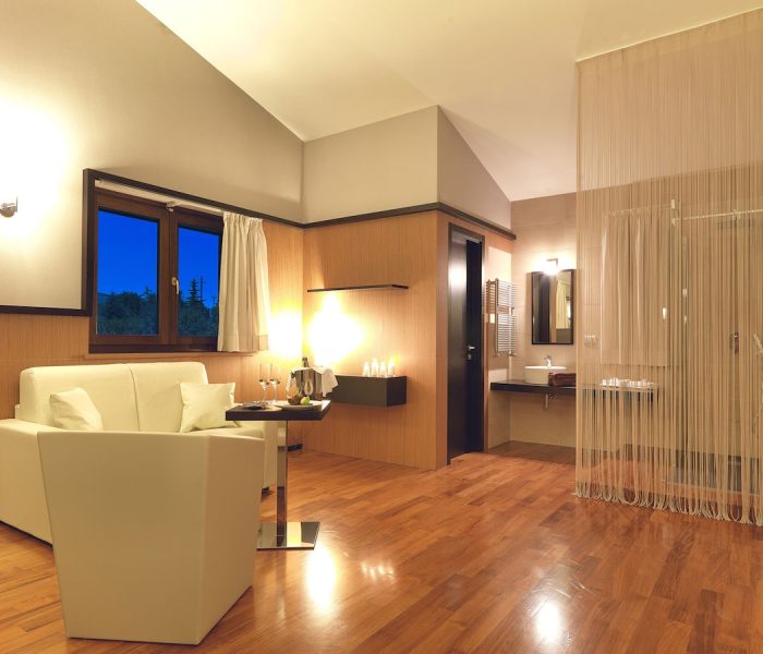 Rilassati nella confortevole area soggiorno della nostra Suite all'Hotel Castagneto Melfi, con una vista incantevole. Elegante area soggiorno della Suite con vista serale all'Hotel Castagneto Melfi.